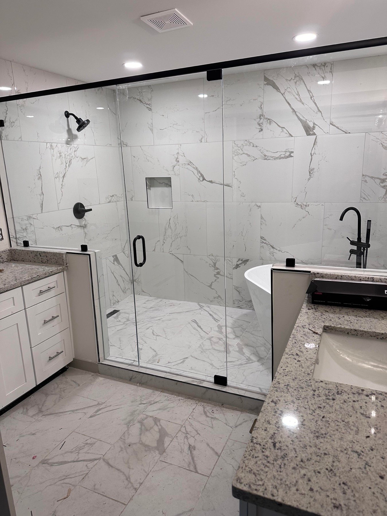 Glass shower enclosure with tile walls and black fixtures