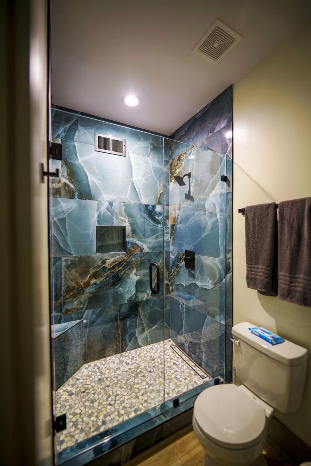 Glass shower enclosure with blue stone-effect tile and black fixtures